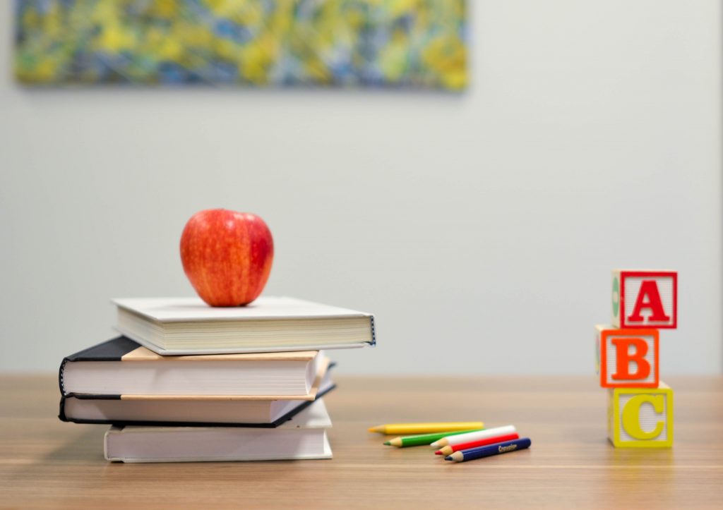 red apple on a stack of four books