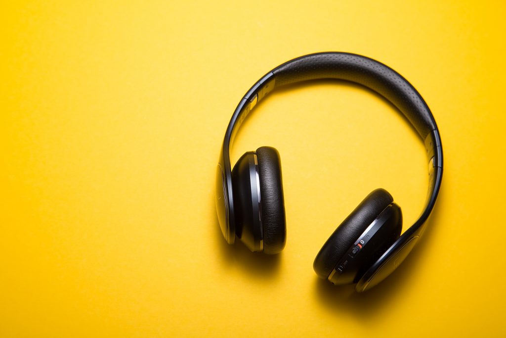 Black over ear headphones lying on a yellow background